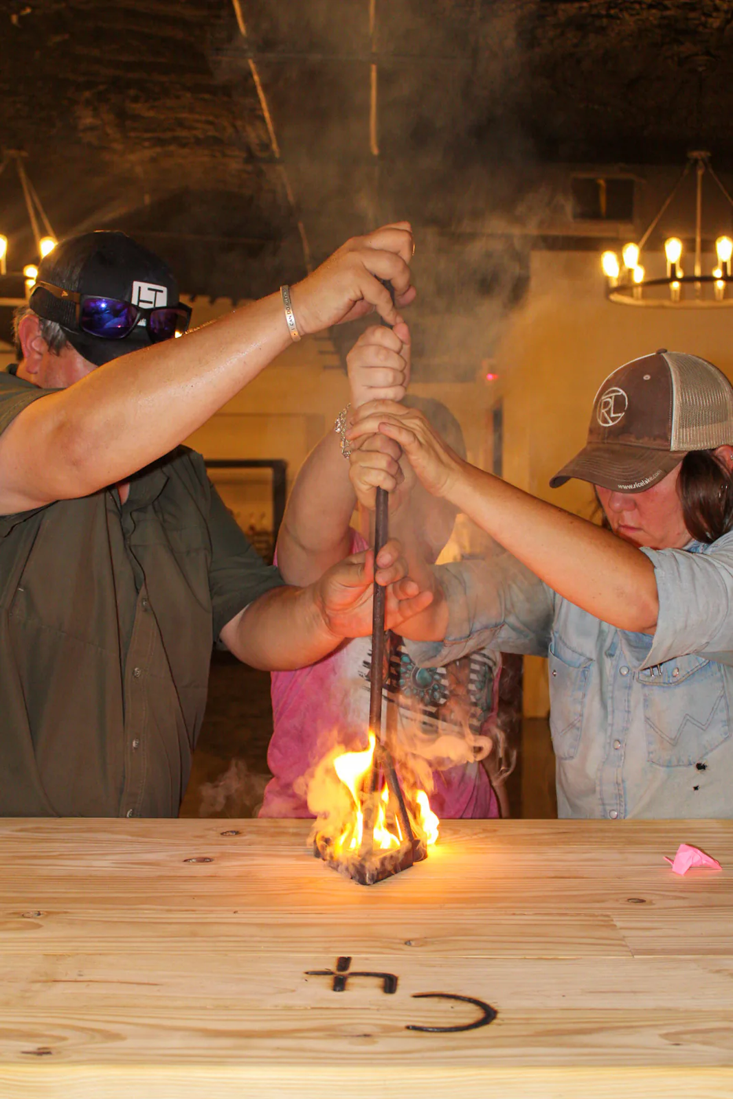 Friends gathered around a flaming branding iron at the bar
