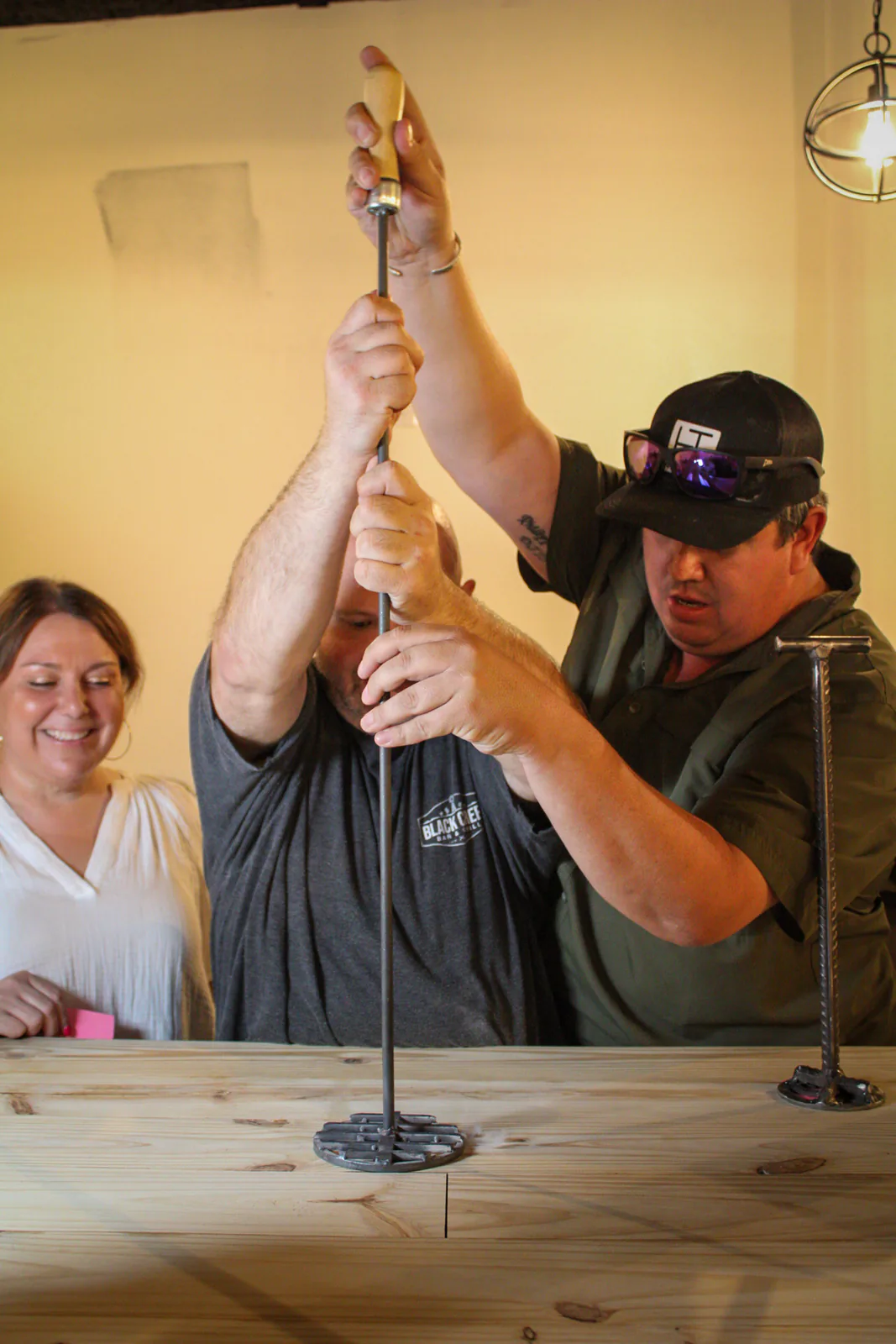 Guests guiding a hot branding iron toward the wooden bar