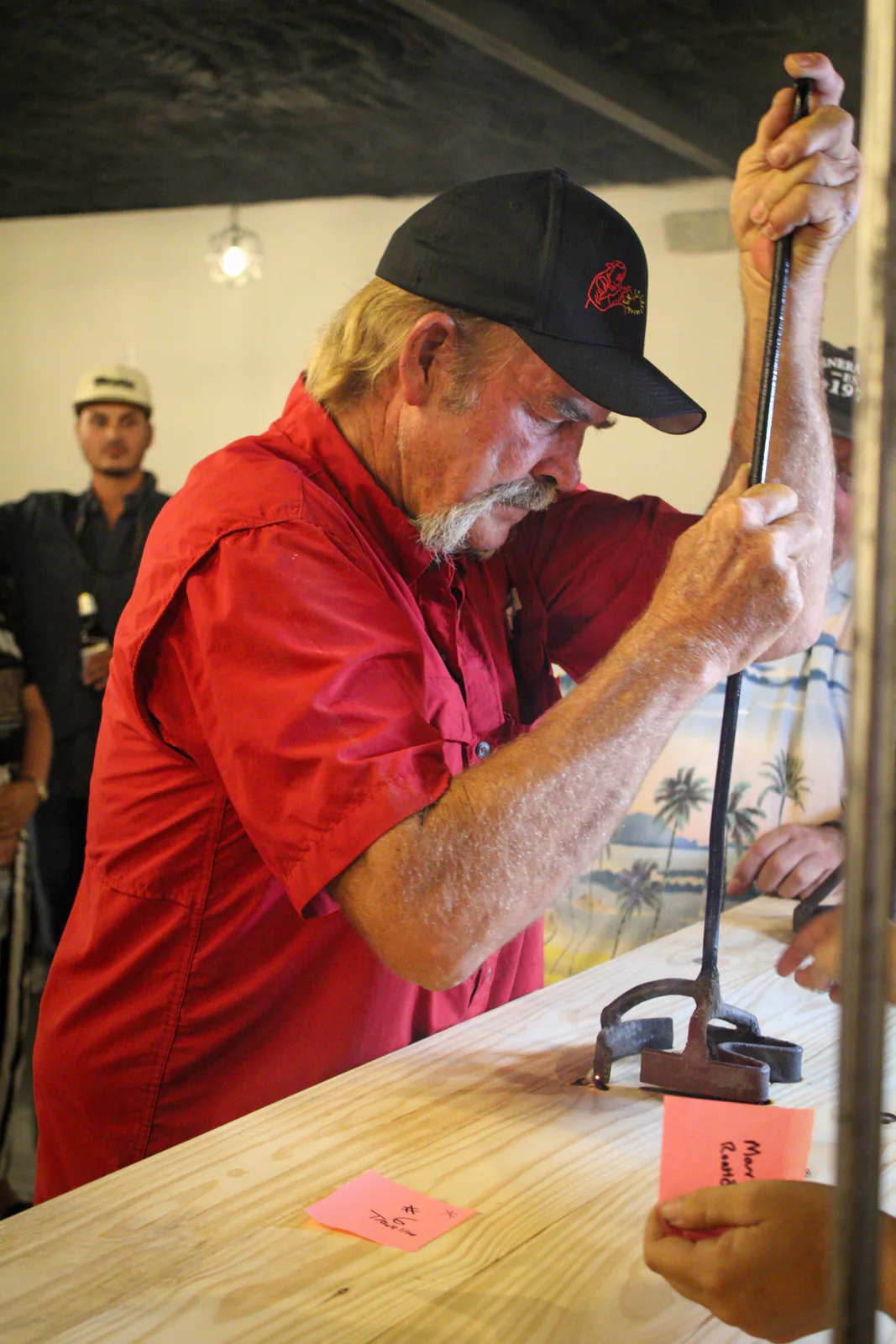 A guest pressing a long-handled branding iron into the bar