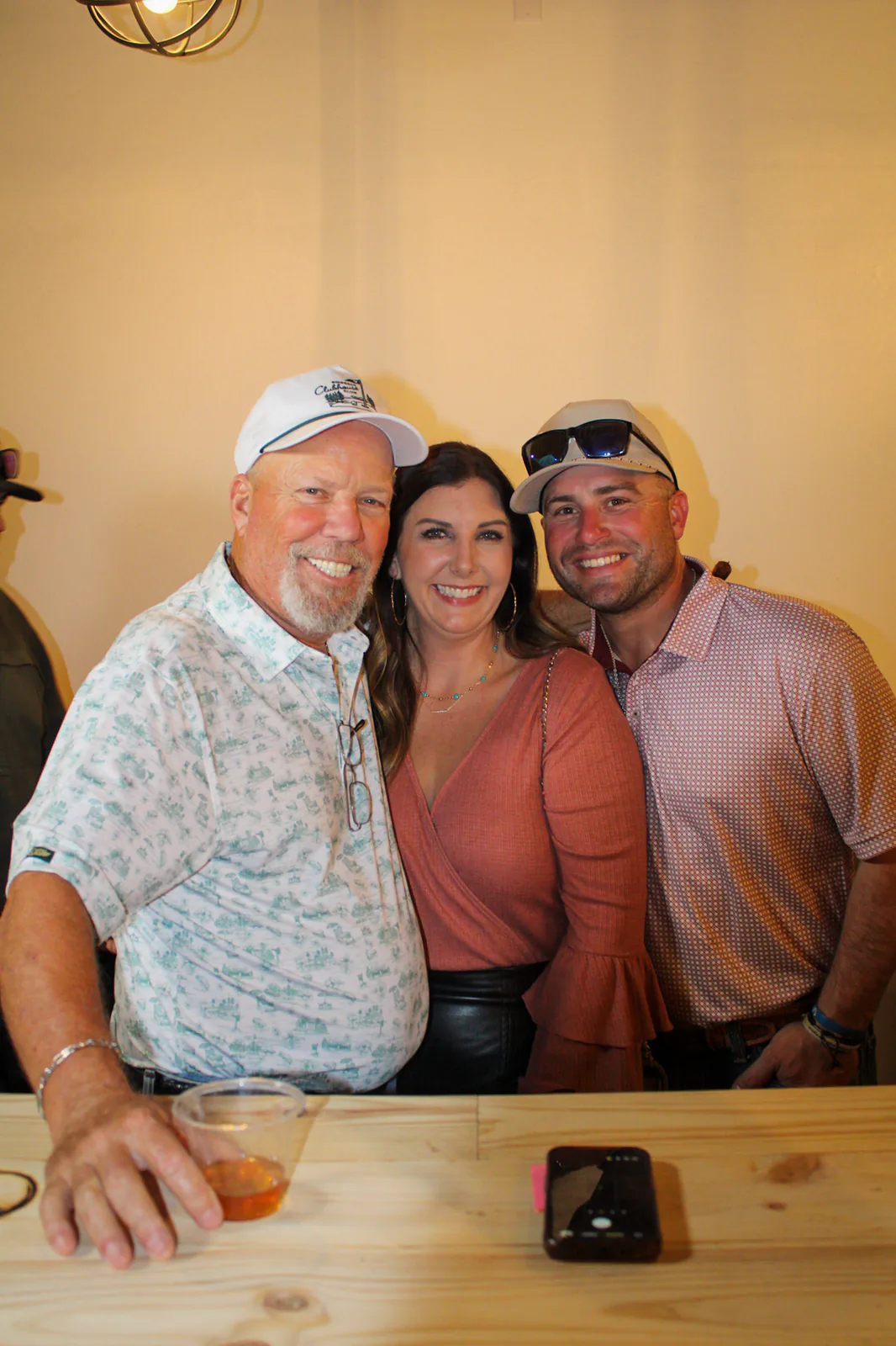 Three guests smiling together at the wooden bar