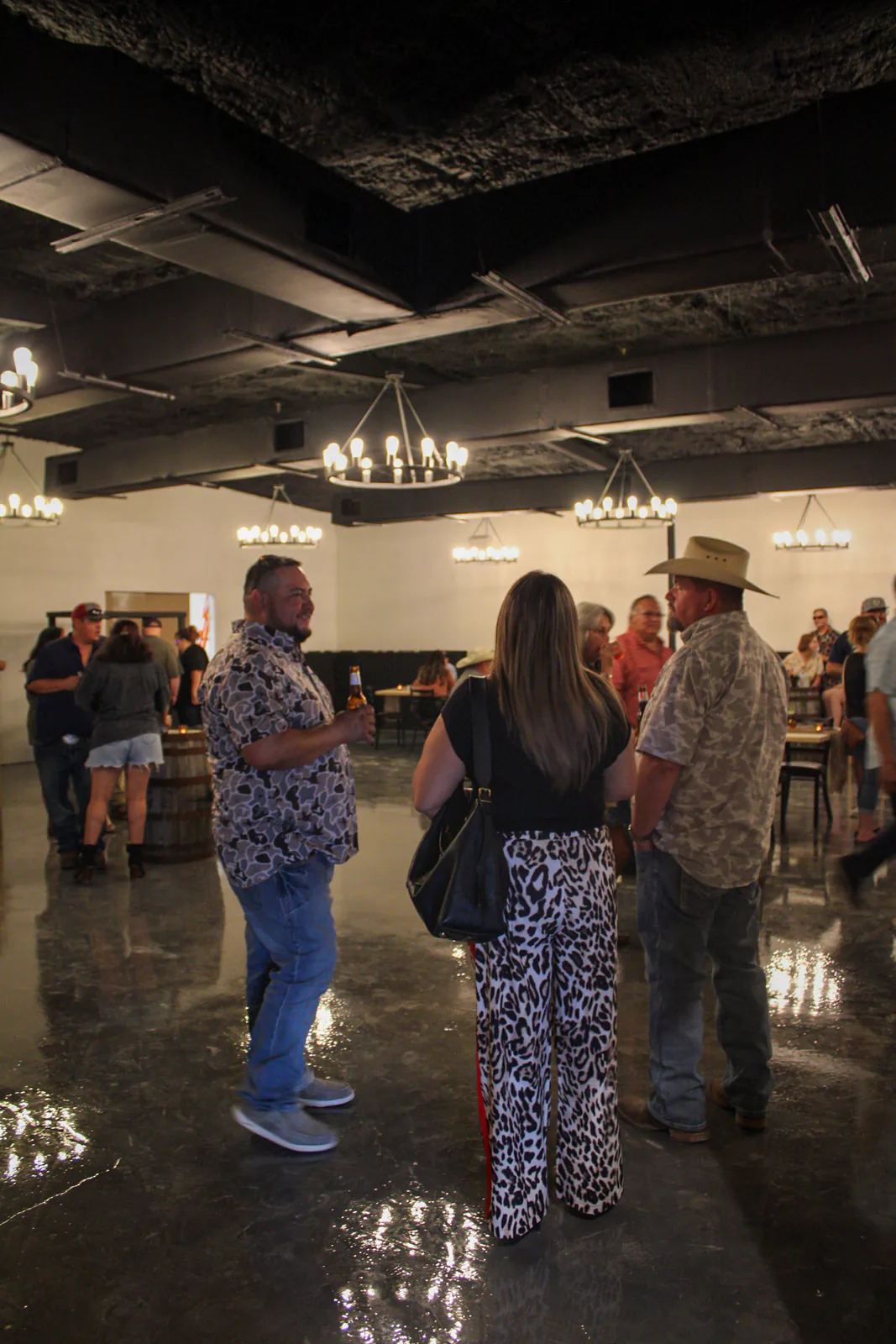 Guests gathering beneath warm lights inside The Warehouse
